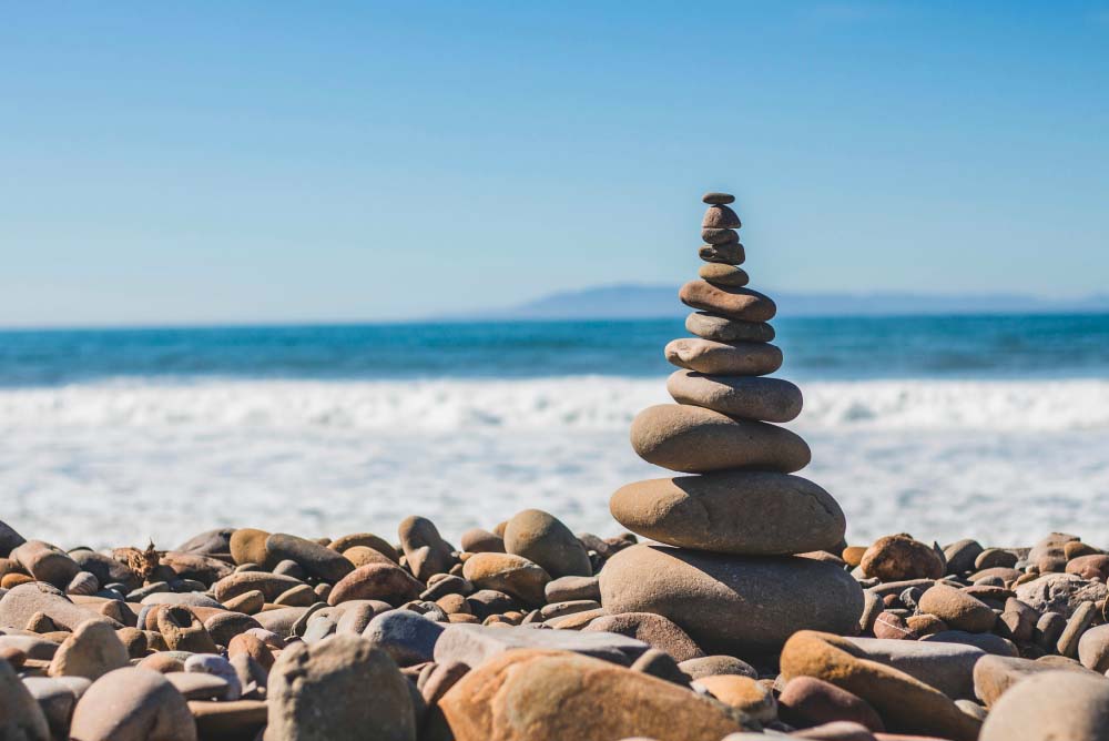 Galets empil&eacute;s en &eacute;quilibre sur une plage, face &agrave; la mer